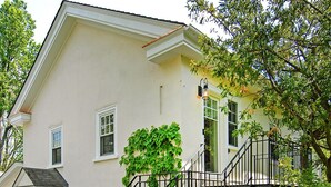 Une maison à deux étages avec un escalier en métal noir menant à la porte d’entrée.