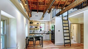 Une cuisine spacieuse avec un dosseret en marbre, un plancher en bois et un réfrigérateur noir.