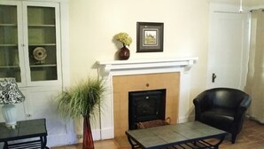 A living room with a fireplace, a black leather chair, a table, a potted plant, and a rug. - 30+Day Stay⭐Lovely Smarthouse King 4KTV W/D WIFI (Klamath Falls)