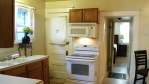 A kitchen with wooden cabinets, a white stove, a microwave, and a sink. - 30+Day Stay⭐Lovely Smarthouse King 4KTV W/D WIFI (Klamath Falls)