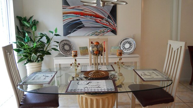 Un coin repas comprenant une table en verre, des chaises, une plante en pot, un globe décoratif et un tableau accroché au mur.