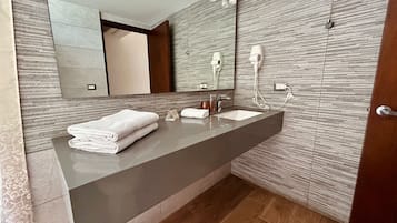 Um banheiro moderno com um espelho grande, um lavatório com bancada escura e piso de madeira.