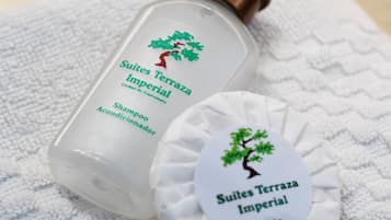 A bottle of shampoo and a round soap bar with a tree logo, both on a white towel.