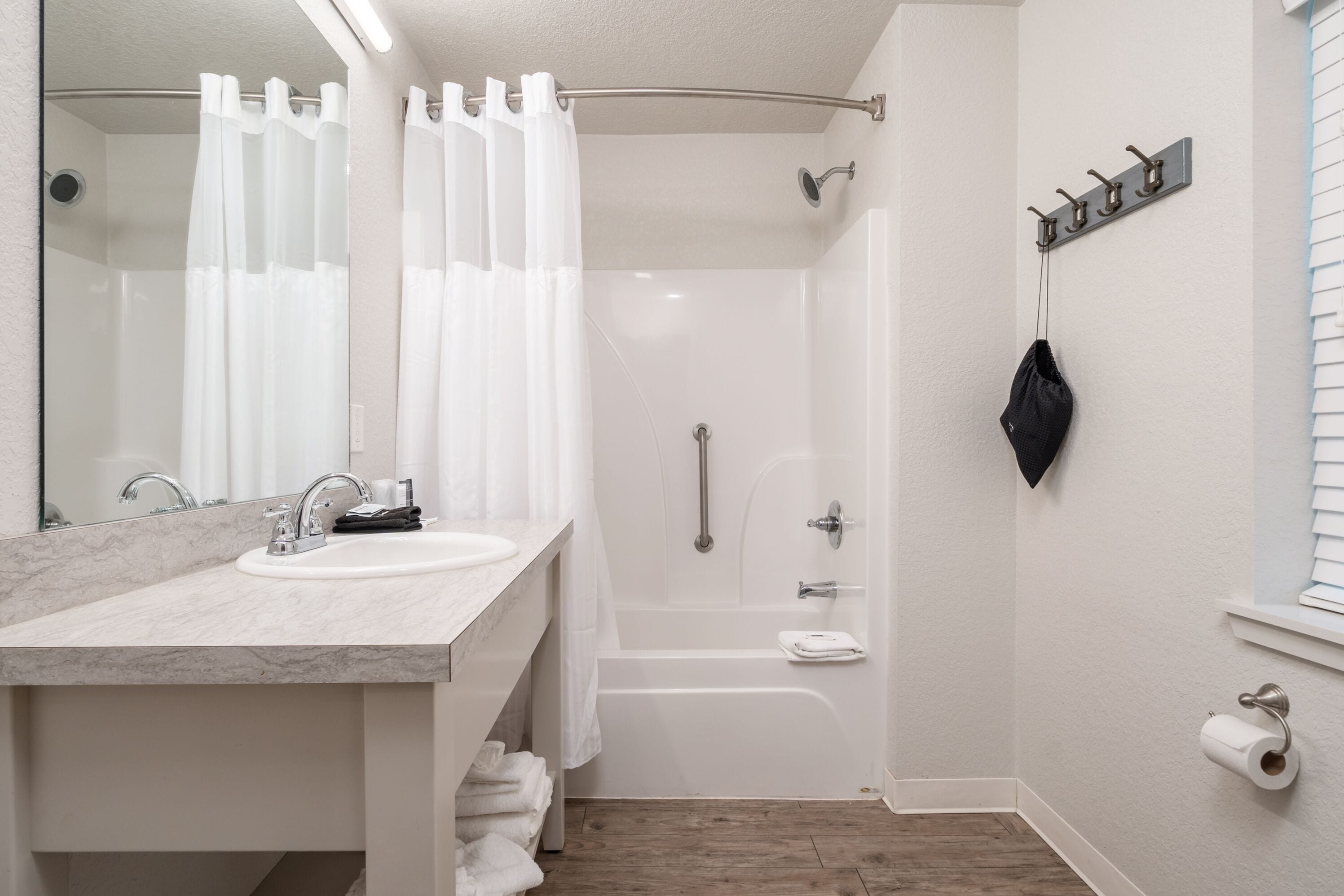 A bathroom with a sink, mirror, shower, and toilet.