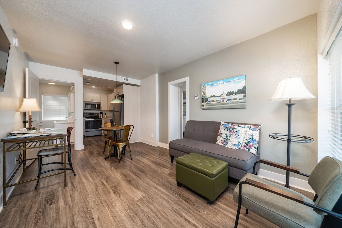 A compact living space with a dining area, kitchenette, and a sofa with a floral pillow.