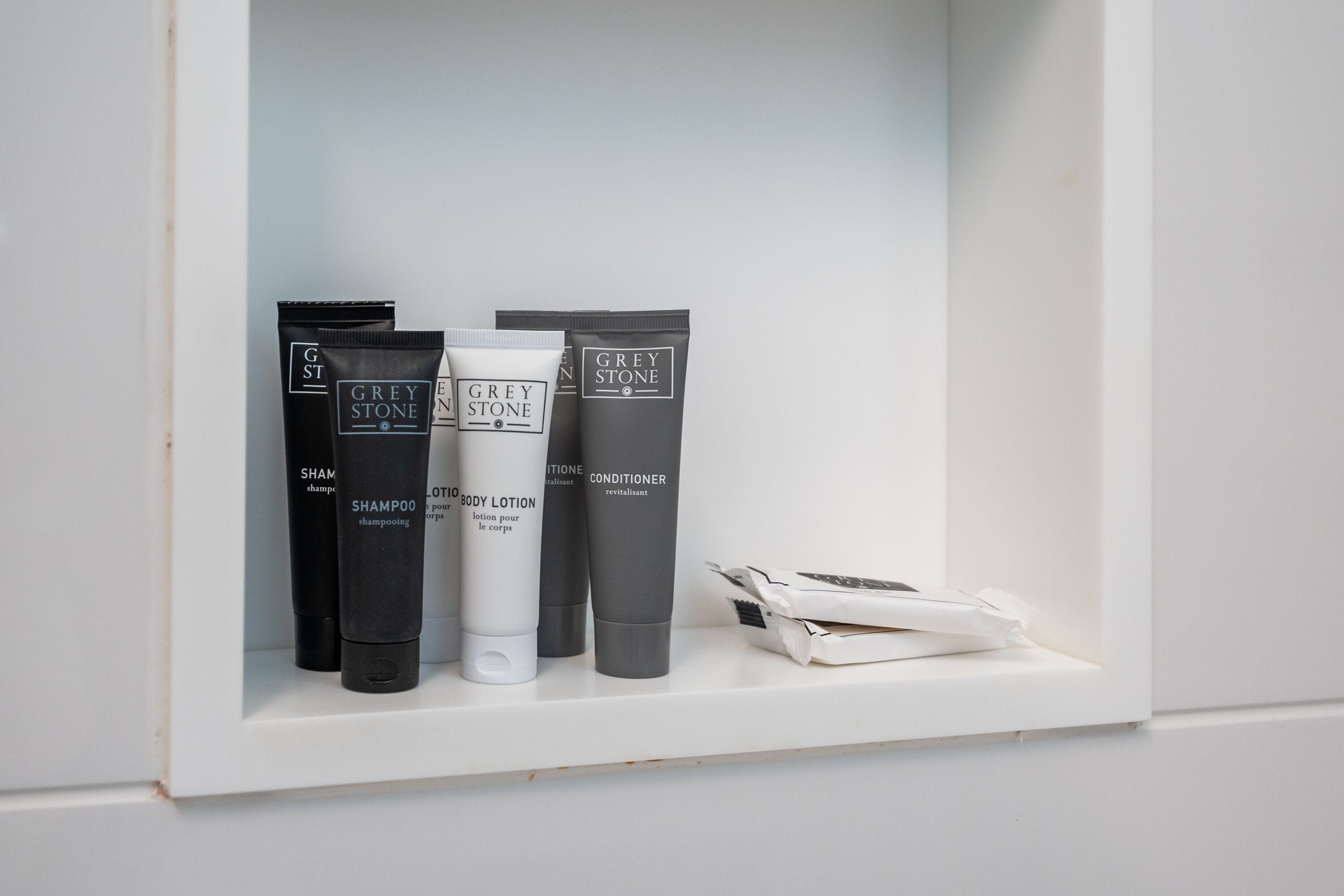 A shelf with Grey Stone shampoo, body lotion, and conditioner.