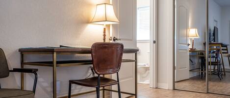 Een kamer met een bureau, een stoel, een lamp en een spiegel.