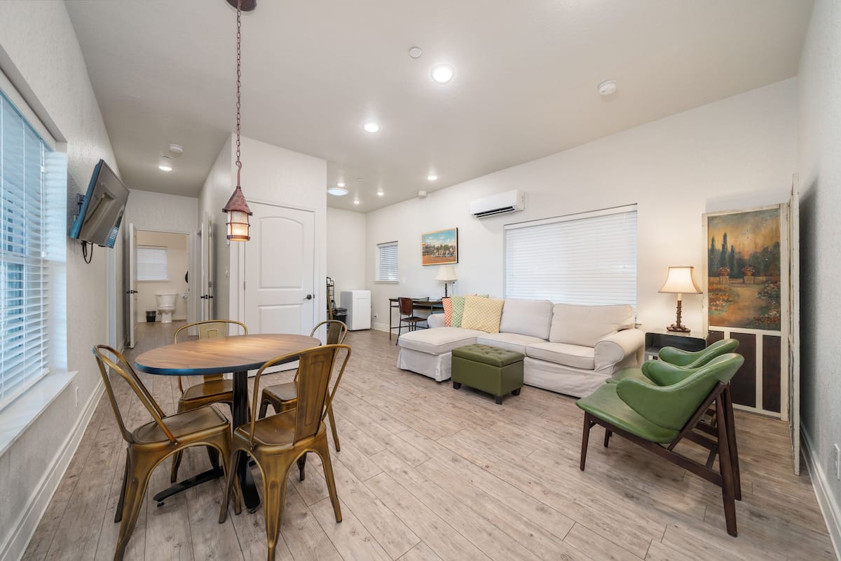 A spacious living area with a dining table, chairs, a sofa, and a green armchair.