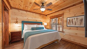 A wooden cabin bedroom with a bed, nightstand, and ceiling fan. - Best  Court (Hot Springs)