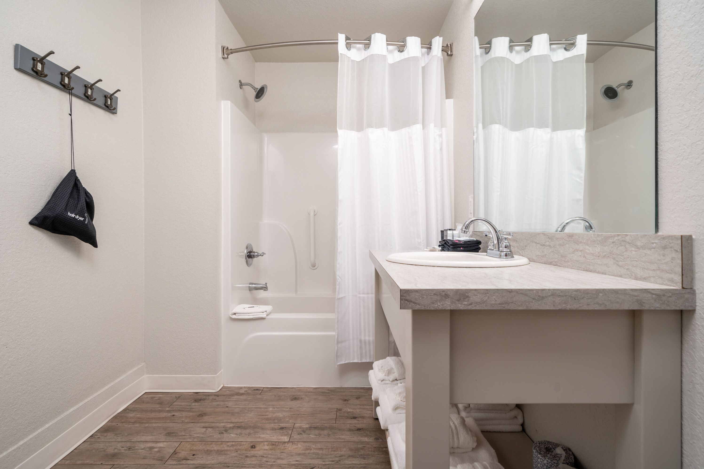 A modern bathroom with a shower, a sink, and a towel rack.