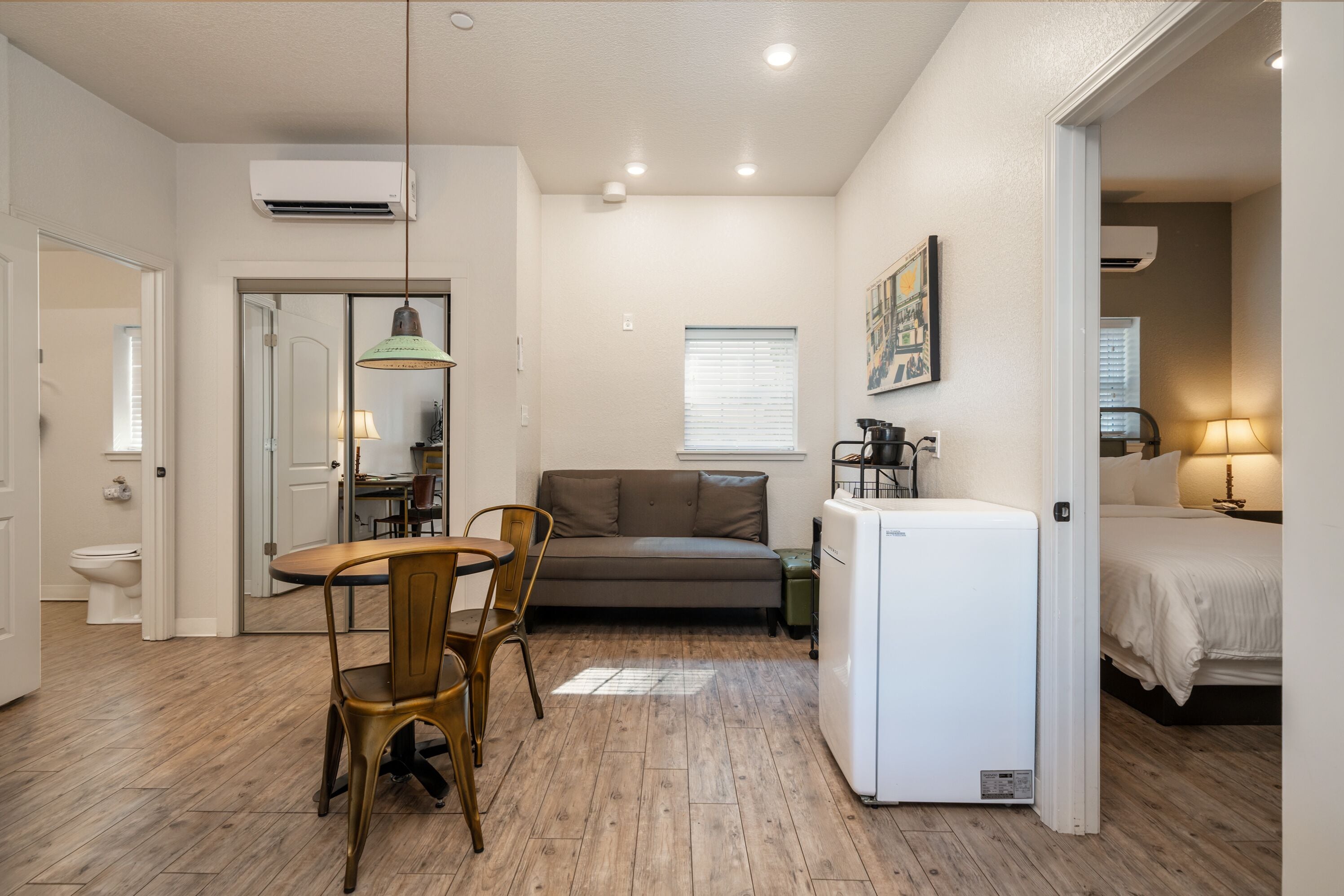 A compact living space with a kitchenette, a dining area with a table and chairs, a sofa, and a bed.