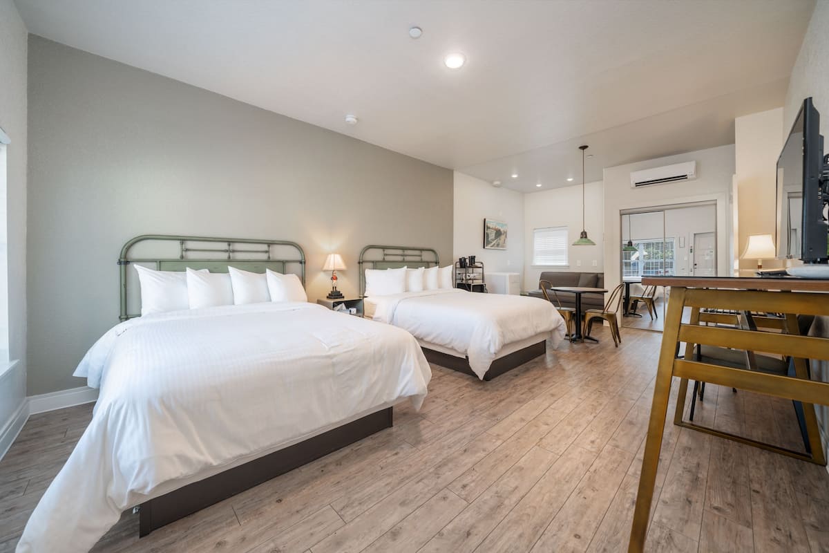 A hotel room with two beds, a dining table, and a TV.