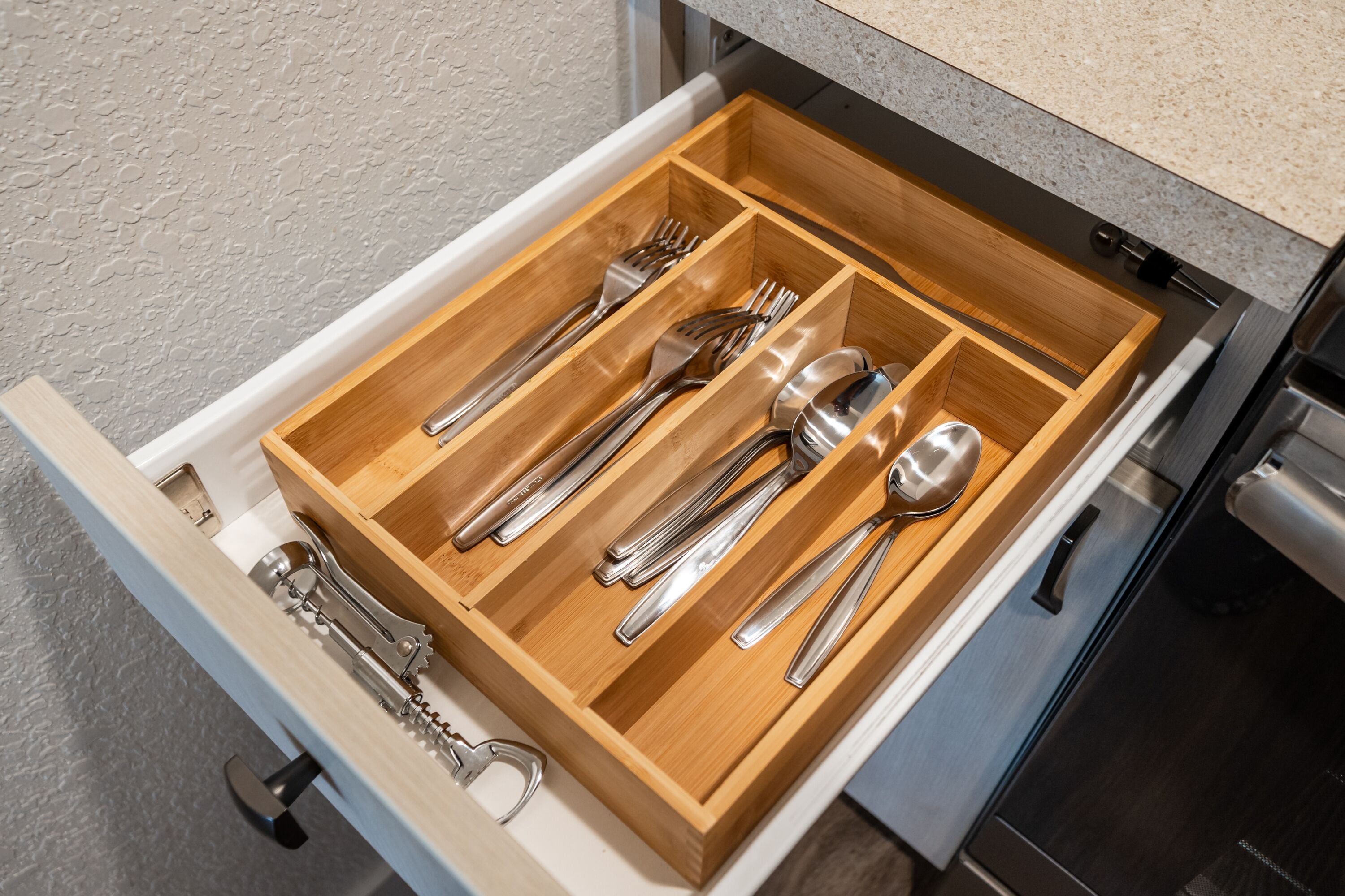 A drawer with compartments containing various utensils.