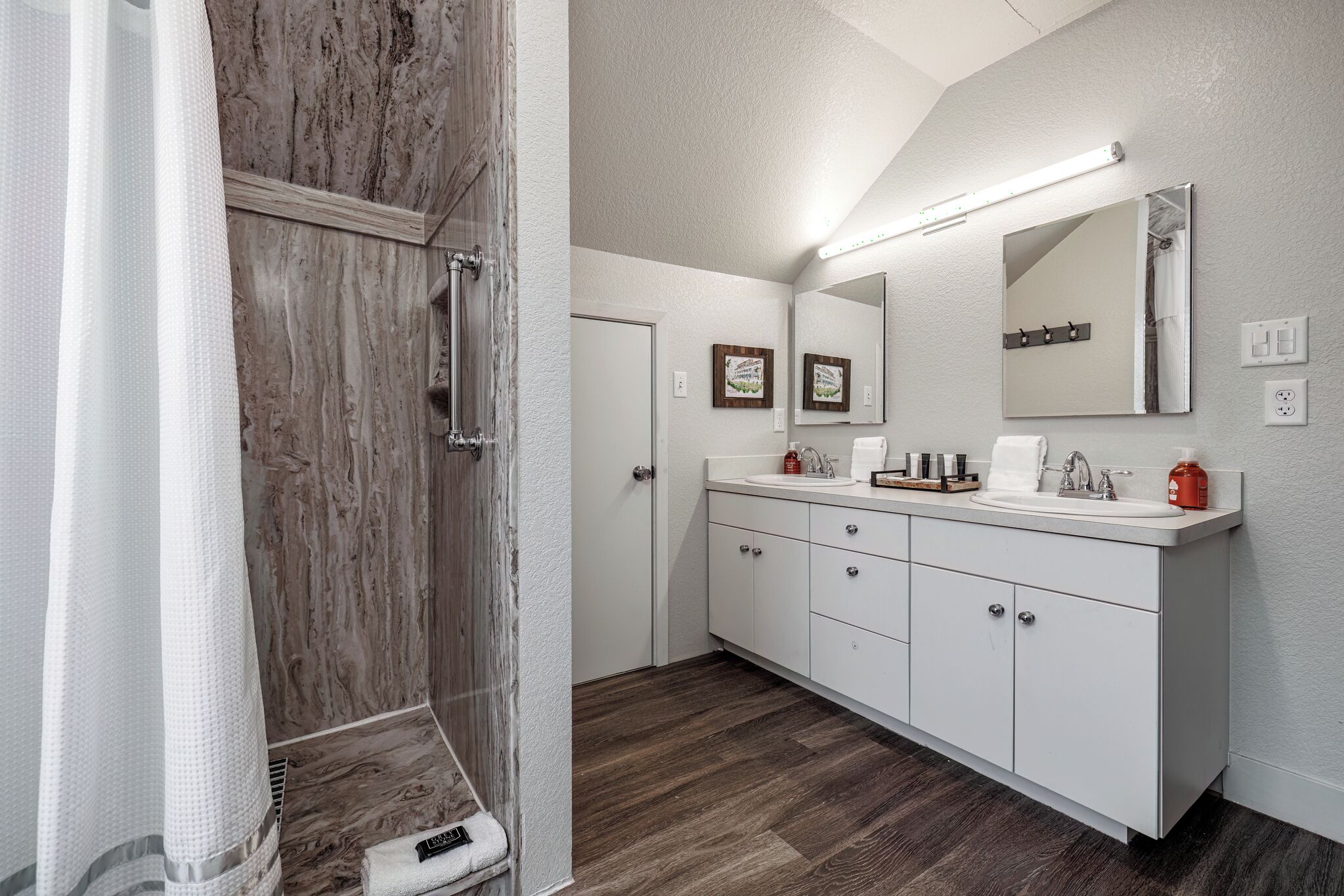 A bathroom with a shower, a sink, a mirror, and a vanity with cabinets.