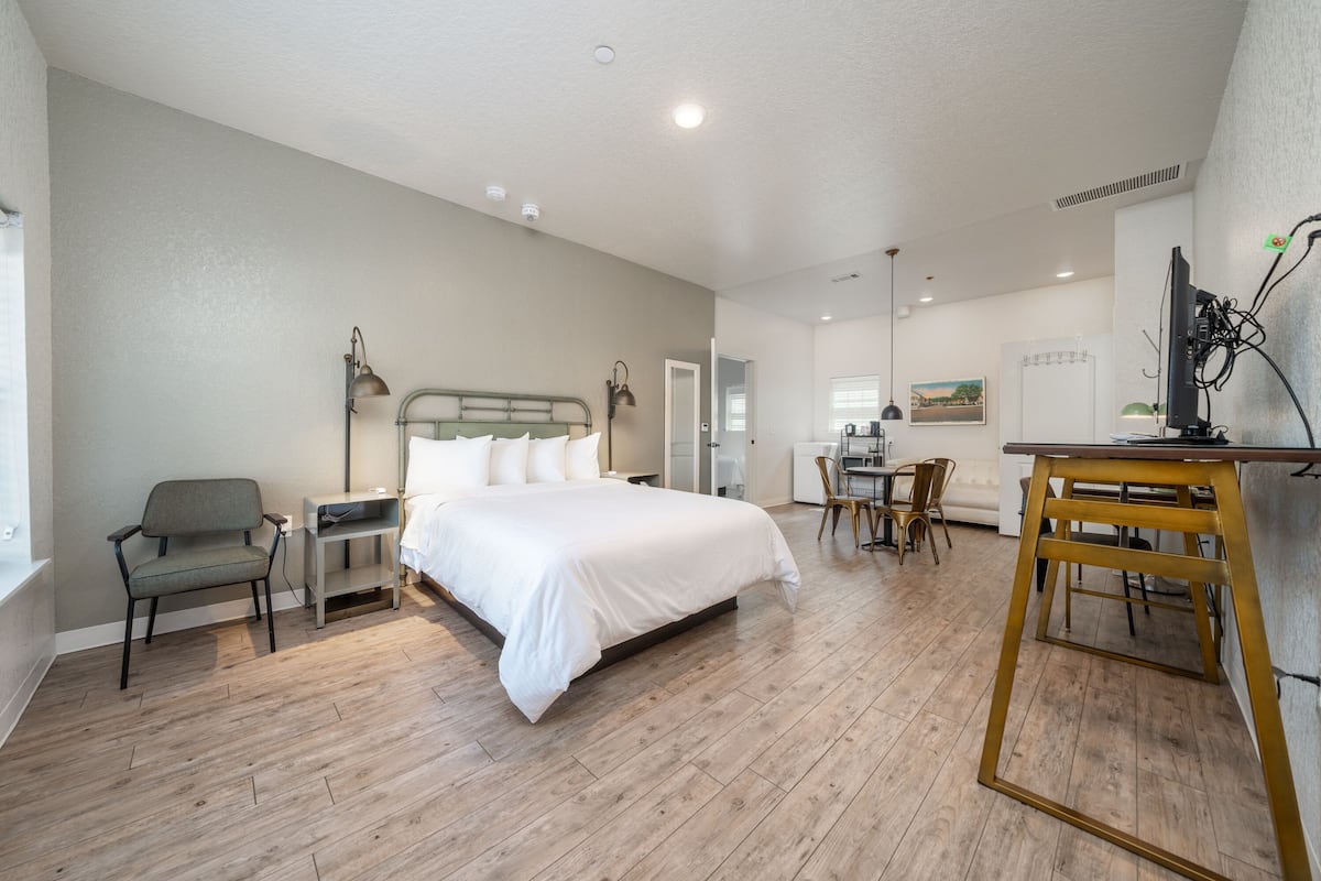 A modern hotel room with a large bed, a desk, and a chair.