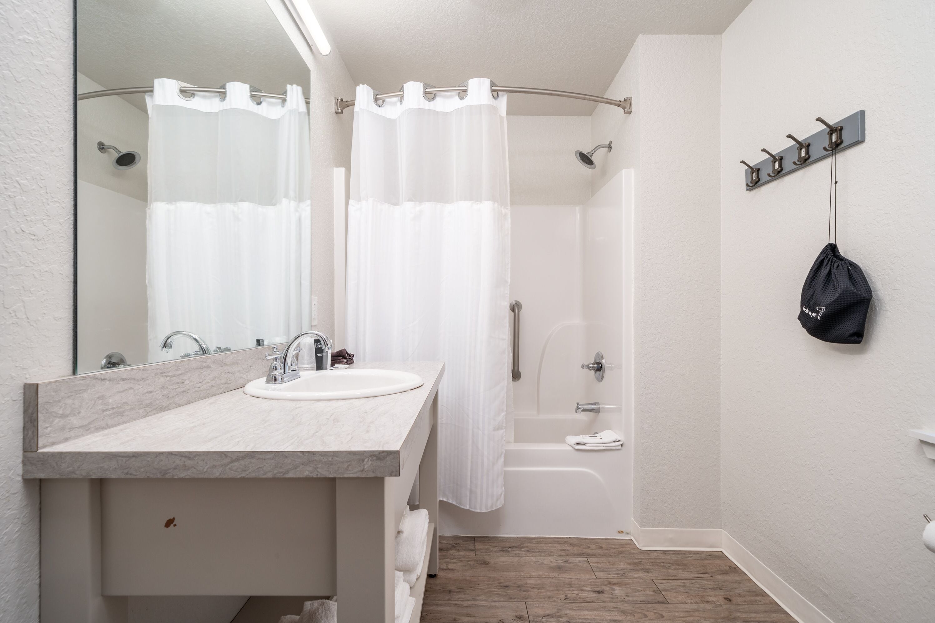 A modern bathroom with a marble sink, a shower with a curtain, and a towel rack on the wall.