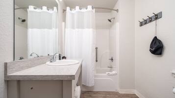 A modern bathroom with a marble sink, a shower with a curtain, and a towel rack on the wall.
