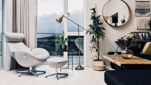 Un salon moderne avec vue sur la ville, un miroir rond, une table ronde agrémentée d’objets décoratifs et un coin salon confortable.