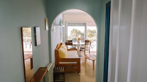 Un couloir menant à un balcon agrémenté d’un banc en bois, de chaises et d’une table.