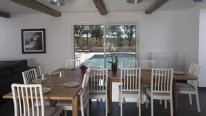 A dining area with a pool view, white chairs, and a wooden table. - AN AIR OF DETENTE **** (4 ears and 4 stars) (Faudoas)