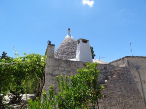 Un edificio in pietra con un tetto a forma di cono e un camino.