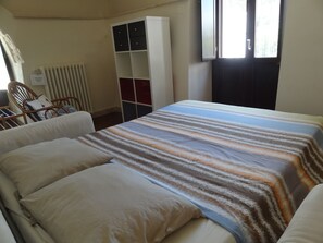 Una camera d'albergo con un letto, un armadio, una sedia e un termosifone.