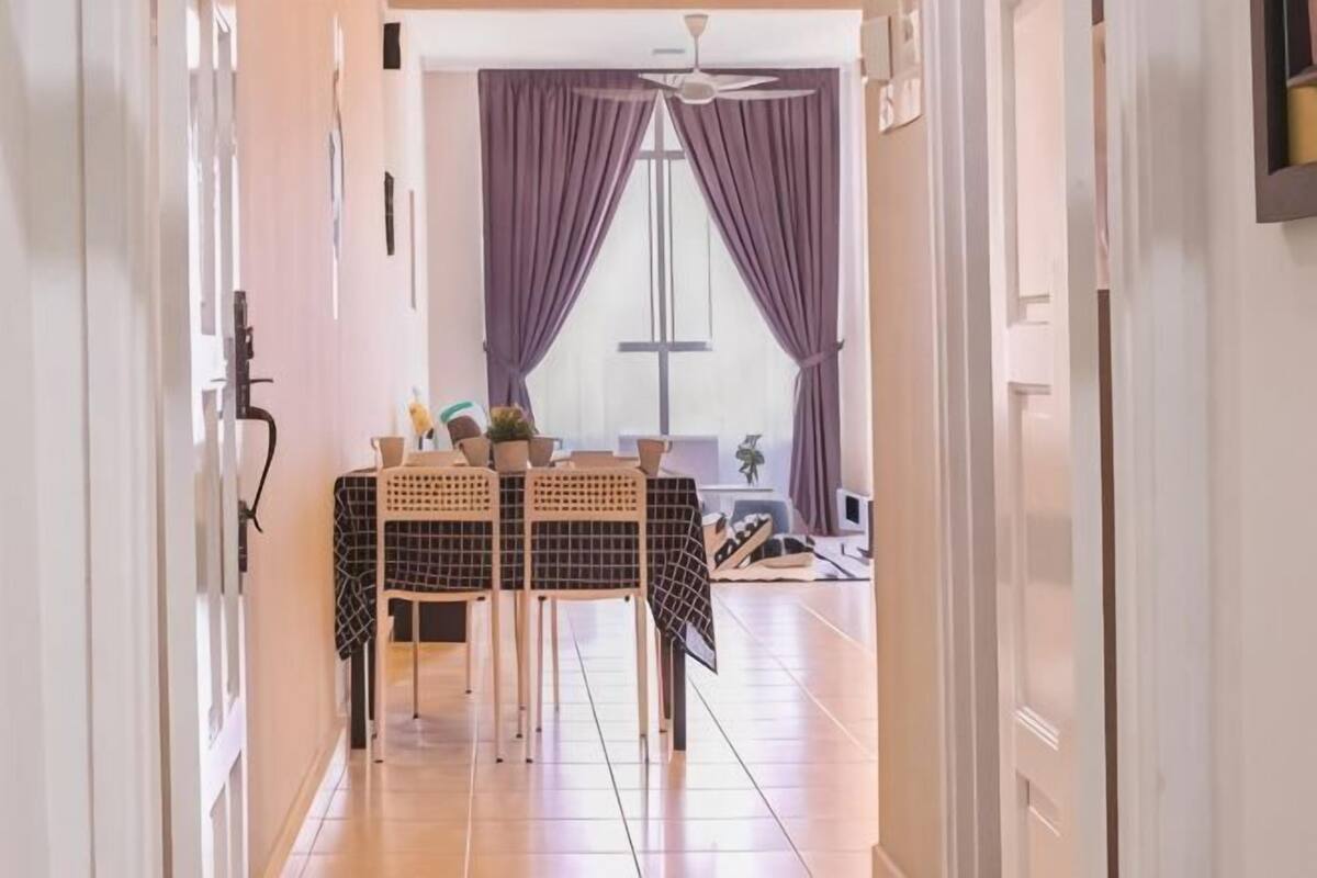 A hallway leading to a dining area with a table and chairs, a ceiling fan, and a window with purple curtains.