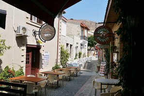 A narrow street with outdoor seating, a clock, and a sign for a restaurant. - Mediterranean dream with sea view and private pool (Pissouri)