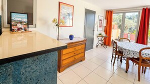 A kitchen with a marble countertop, wooden cabinets, a dining area with a table and chairs, and a view through a glass door. - CEZANNE: Quiet location with a beautiful, unobstructed view, 300 meters from the beaches and shops. Wi-Fi. (Collioure)