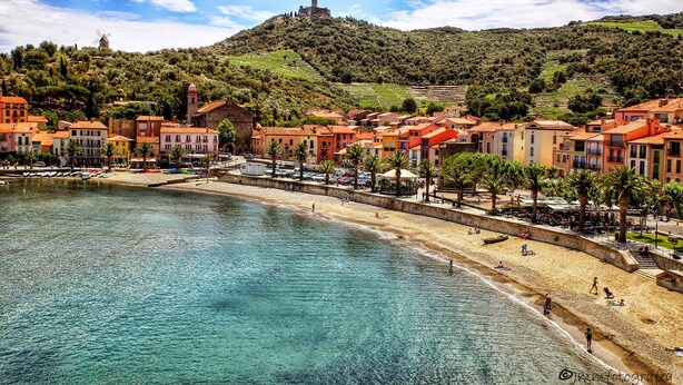 A coastal town with a beach, buildings with red-tiled roofs, and a hill with a tower. - CEZANNE: Quiet location with a beautiful, unobstructed view, 300 meters from the beaches and shops. Wi-Fi. (Collioure)