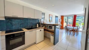 A modern kitchen with a dishwasher, oven, and a dining area with a table and chairs. - CEZANNE: Quiet location with a beautiful, unobstructed view, 300 meters from the beaches and shops. Wi-Fi. (Collioure)