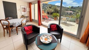 A room with a dining table, two chairs, a small table with a plate, and a view of a balcony with outdoor furniture. - CEZANNE: Quiet location with a beautiful, unobstructed view, 300 meters from the beaches and shops. Wi-Fi. (Collioure)