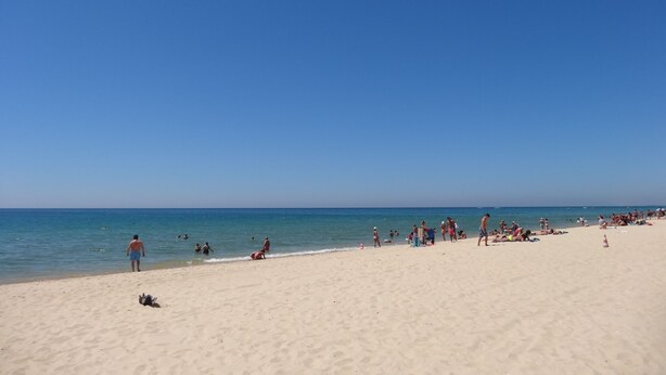 A beach with people sunbathing and swimming. - New 3-bedroom apartment 50 meters from the beach (Vila Real de Santo António)