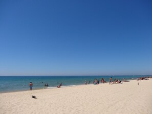 Uma praia com pessoas tomando sol e nadando.