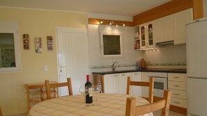 Une cuisine avec une table à manger pour deux personnes, un réfrigérateur et des armoires blanches.