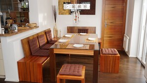 Ein Essbereich mit einem Holztisch, gedeckt für vier Personen, umgeben von gepolsterten Sitzgelegenheiten.