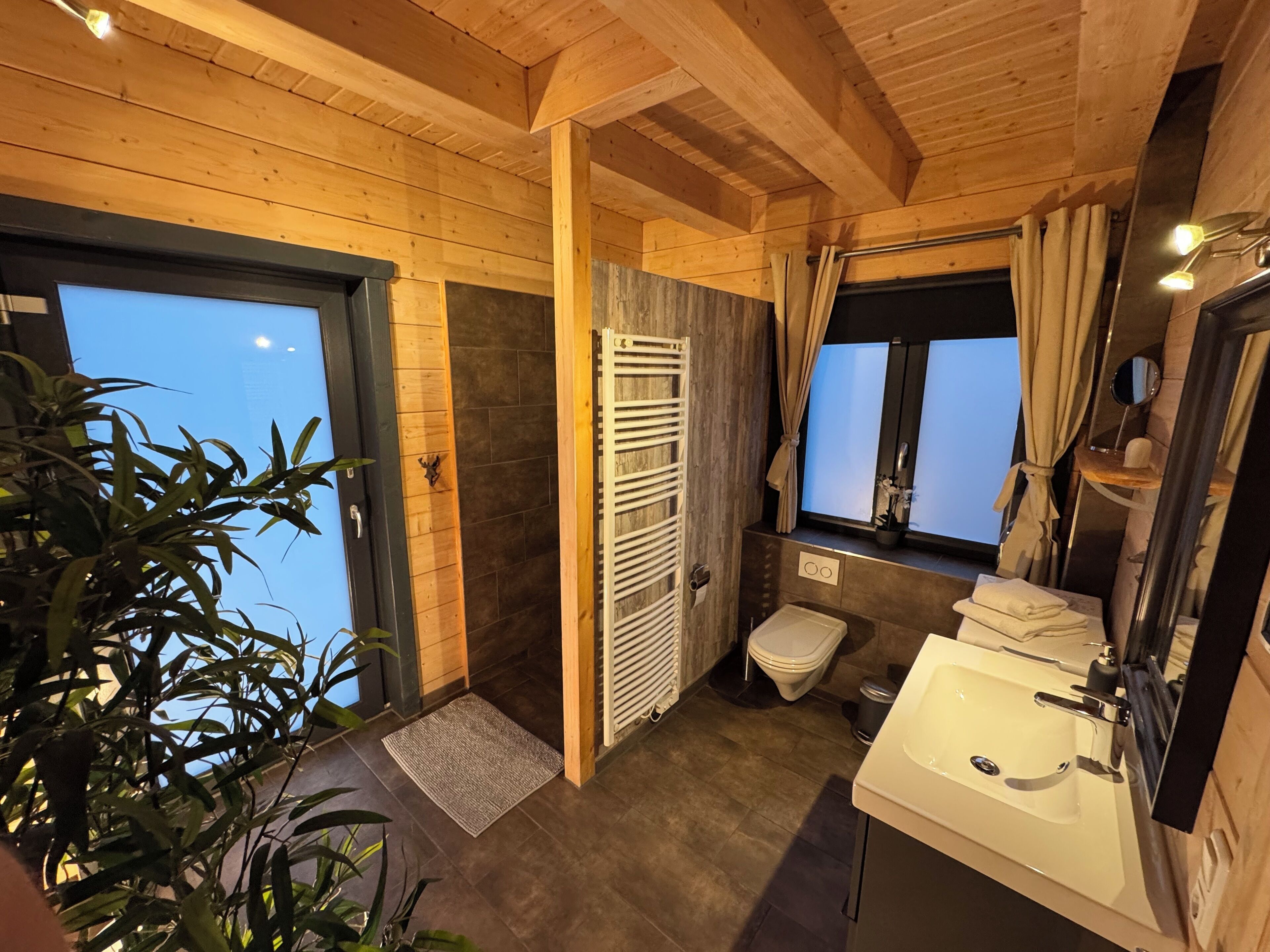 Interior de madeira com banheiro, incluindo vaso sanitário, pia e porta-toalhas.