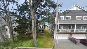 Un quartier résidentiel avec une maison à deux étages, une terrasse en bois et une cour gazonnée.