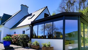 Ein modernes Haus mit Wintergarten, weißen Wänden und einem Schotterweg.