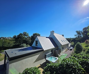 A house with a sloped roof, a visible attic window, and a small outdoor seating area with a table and chairs.