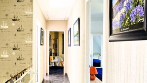 Ein Hotelgang mit Fliesenboden, einer Treppe mit Geländer und einem gerahmten Bild an der Wand.