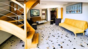 Eine Treppe mit hölzernen Geländern, ein gelbes Sofa, ein Couchtisch und ein Gemälde von Booten an der Wand.