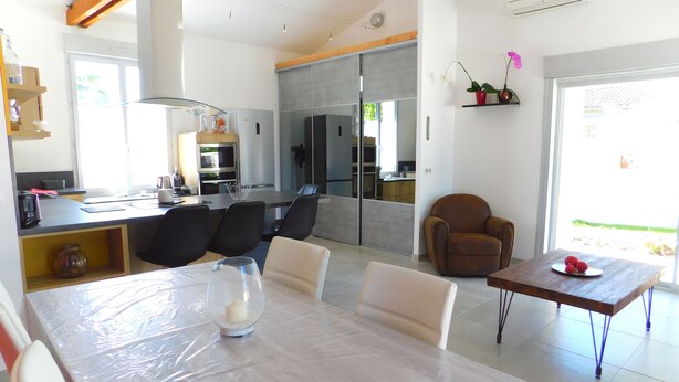 A modern kitchen with a dining area, featuring a large table, chairs, and a small side table with fruit. - The oustaou of Sandrine (Valréas)