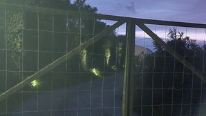 Ein eingezäunter Bereich mit einem Kiesweg und Bäumen im Hintergrund.