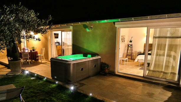 Ein Außenpoolbereich mit Whirlpool, Esstisch und Stühlen.