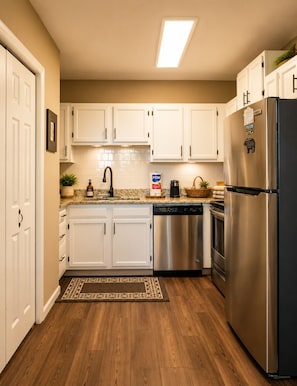 A kitchen with white cabinets, stainless steel appliances, a dishwasher, and a refrigerator.