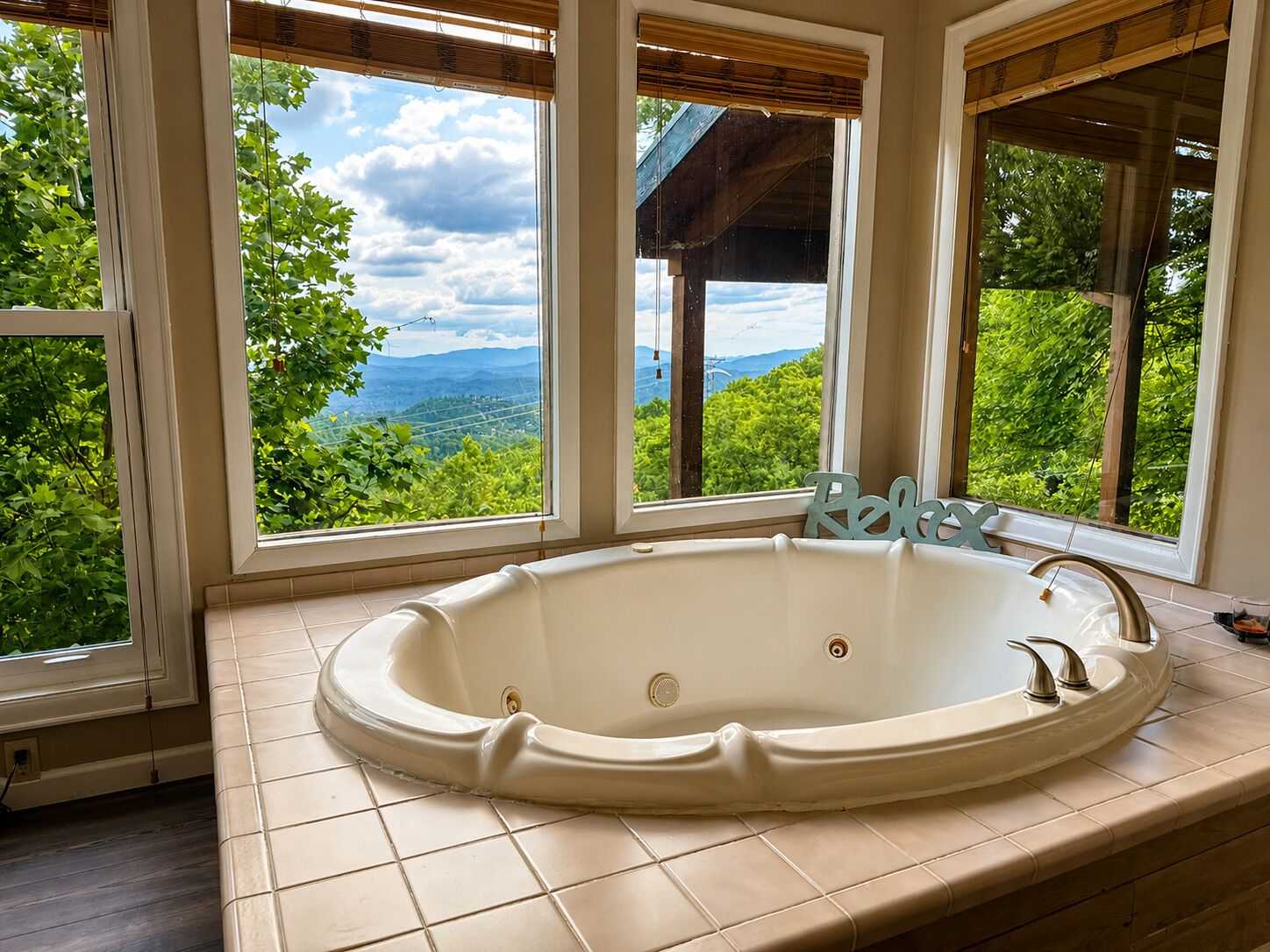 A bathroom with a freestanding bathtub, large windows, and a view of a mountainous landscape.