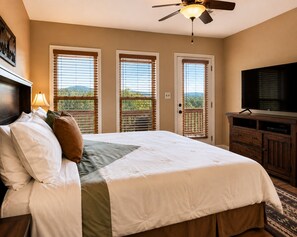 A hotel room with a bed, a television, a ceiling fan, and a view of the outdoors through the windows. - Worth The Climb, Hot tub, bears and Views! (Gatlinburg)