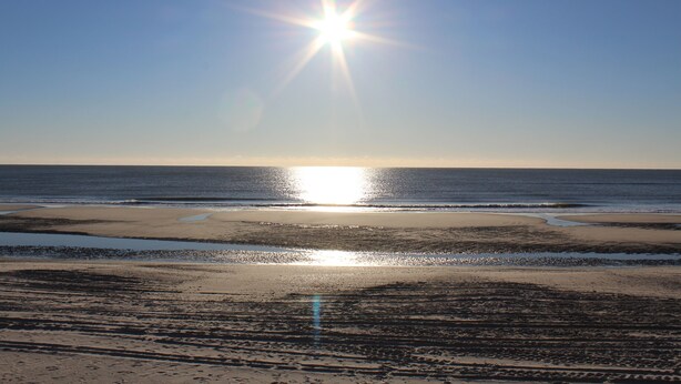 En strand med solskin over vandet.