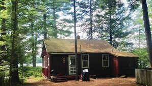 Ein rustikales Blockhaus mit Holzwand, Schornstein und ein Veranda.